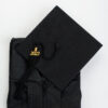 Black graduation gown folded beside a matching mortarboard cap with a gold tassel on a white background.